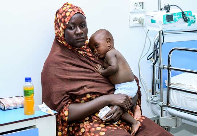 A Sudanese mother holds her young child at a medical facility in Sudan.What is Trump's travel ban?